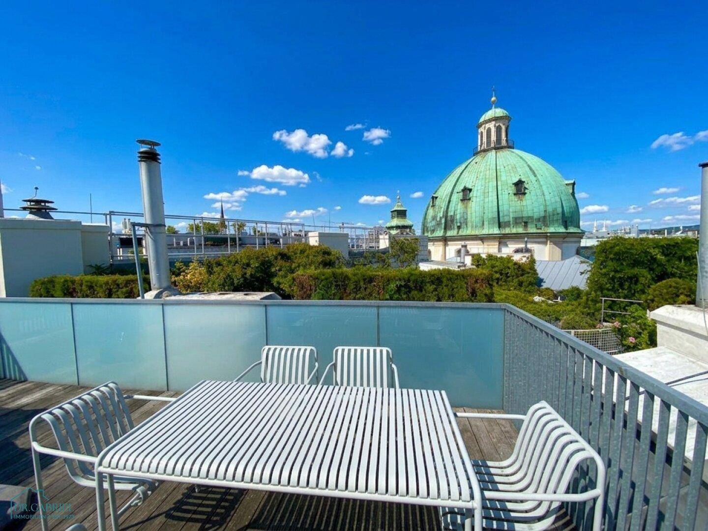 Dachterrasse mit Sitzgelegenheiten und weitem Blick über die Stadt und historische Gebäude.