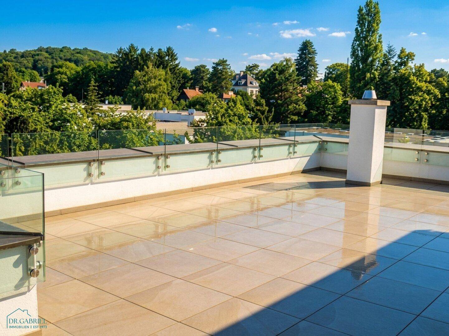 Große, sonnige Dachterrasse mit modernen Glasgeländern und weitem Blick ins Grüne.