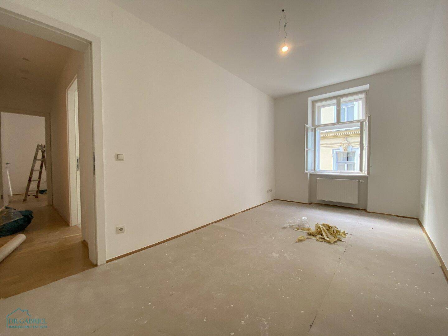 Heller, leerer Raum mit einem Fenster und vorbereitetem Boden, ideal für ein Schlaf- oder Arbeitszimmer.