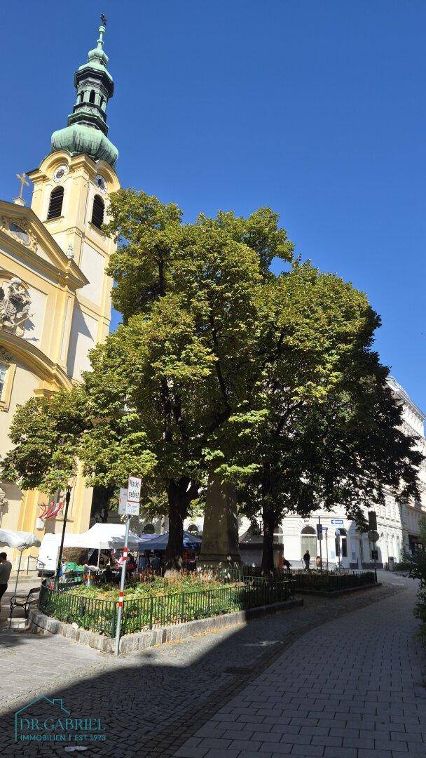 Malerische Straßenansicht mit historischer Kirche, Bäumen und blauem Himmel.