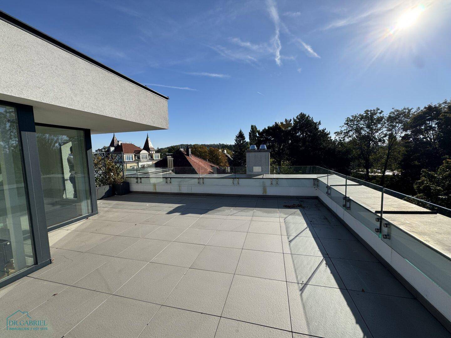 Weitläufige Dachterrasse mit Fliesen und Glasgeländer, ideal für Entspannung im Freien.