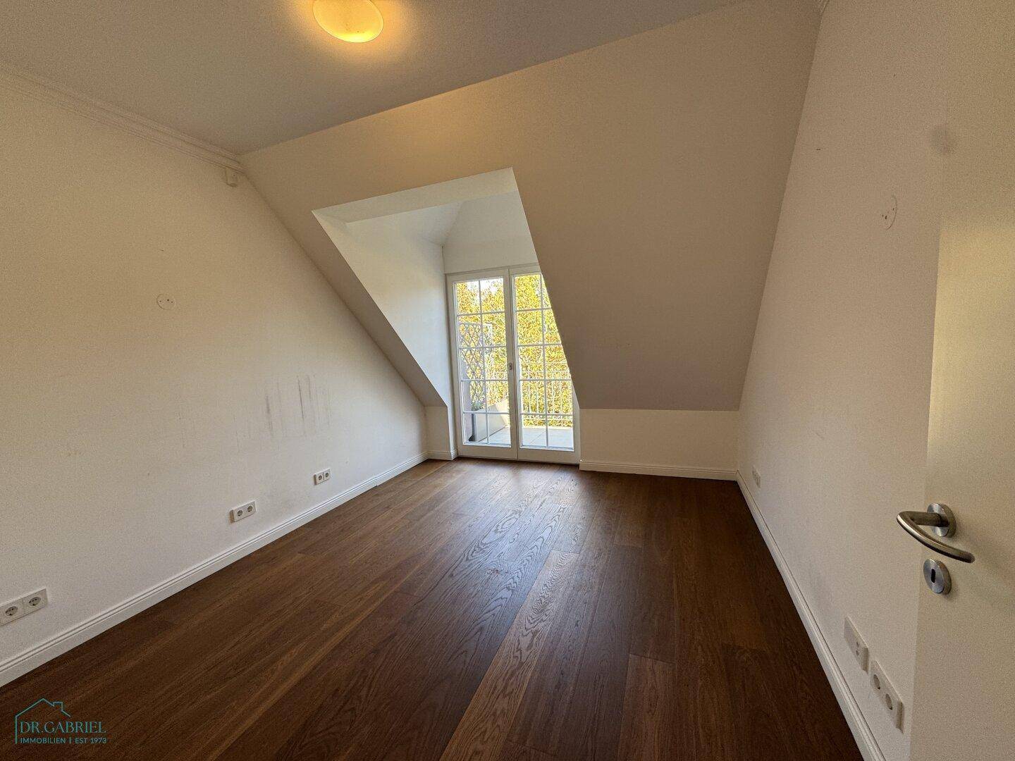 Helles Zimmer mit Holzboden und französischem Balkon, bietet viel natürliches Licht.
