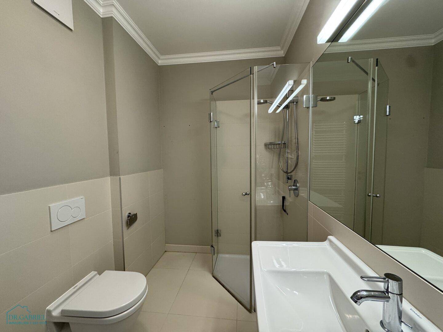 Modernes Badezimmer mit Duschkabine, Waschbecken und wandhängender Toilette.