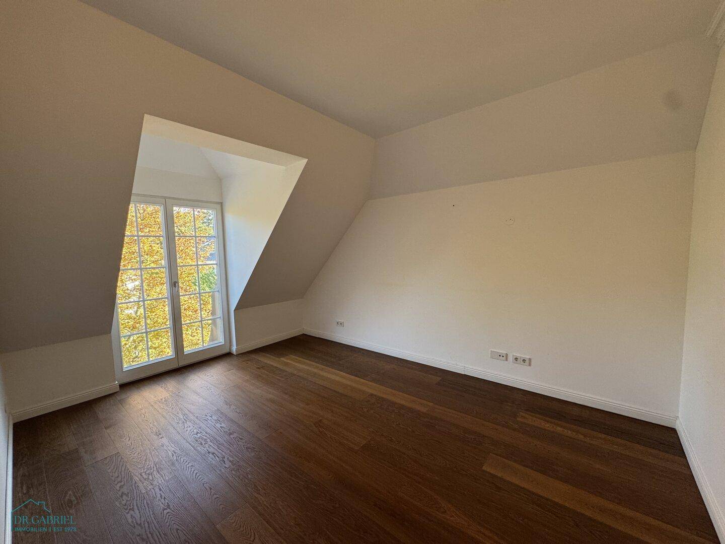Helles Zimmer mit Holzboden und französischem Balkon, bietet viel natürliches Licht.