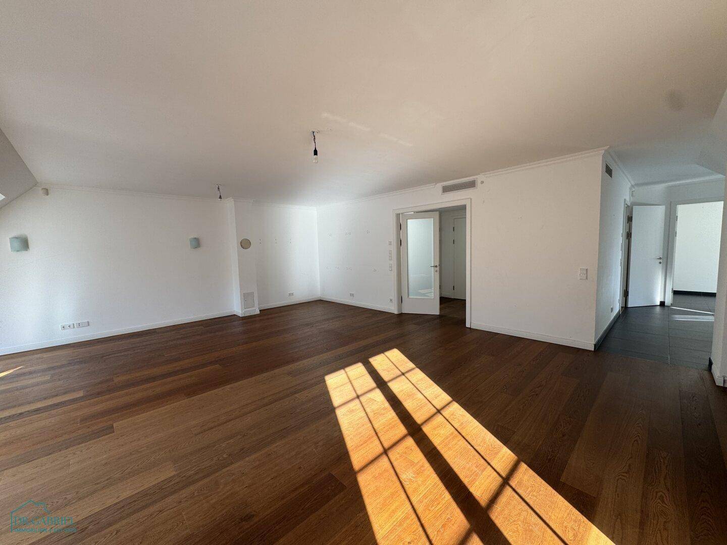 Heller Wohnbereich mit Holzboden und Zugang zu weiteren Räumen sowie einem Fenster.