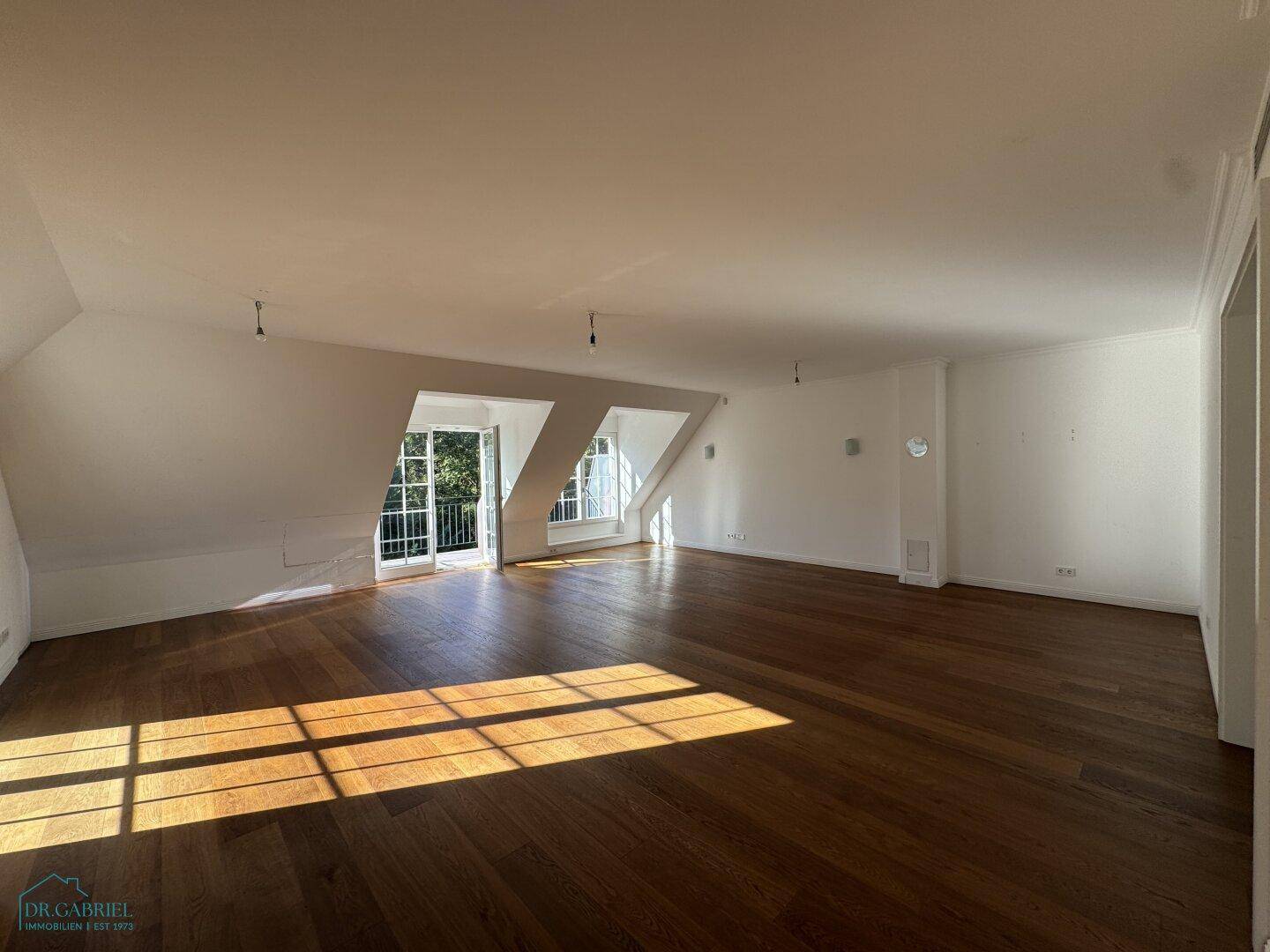 Geräumiger, heller Wohnbereich im Dachgeschoss mit Holzboden und viel natürlichem Licht.