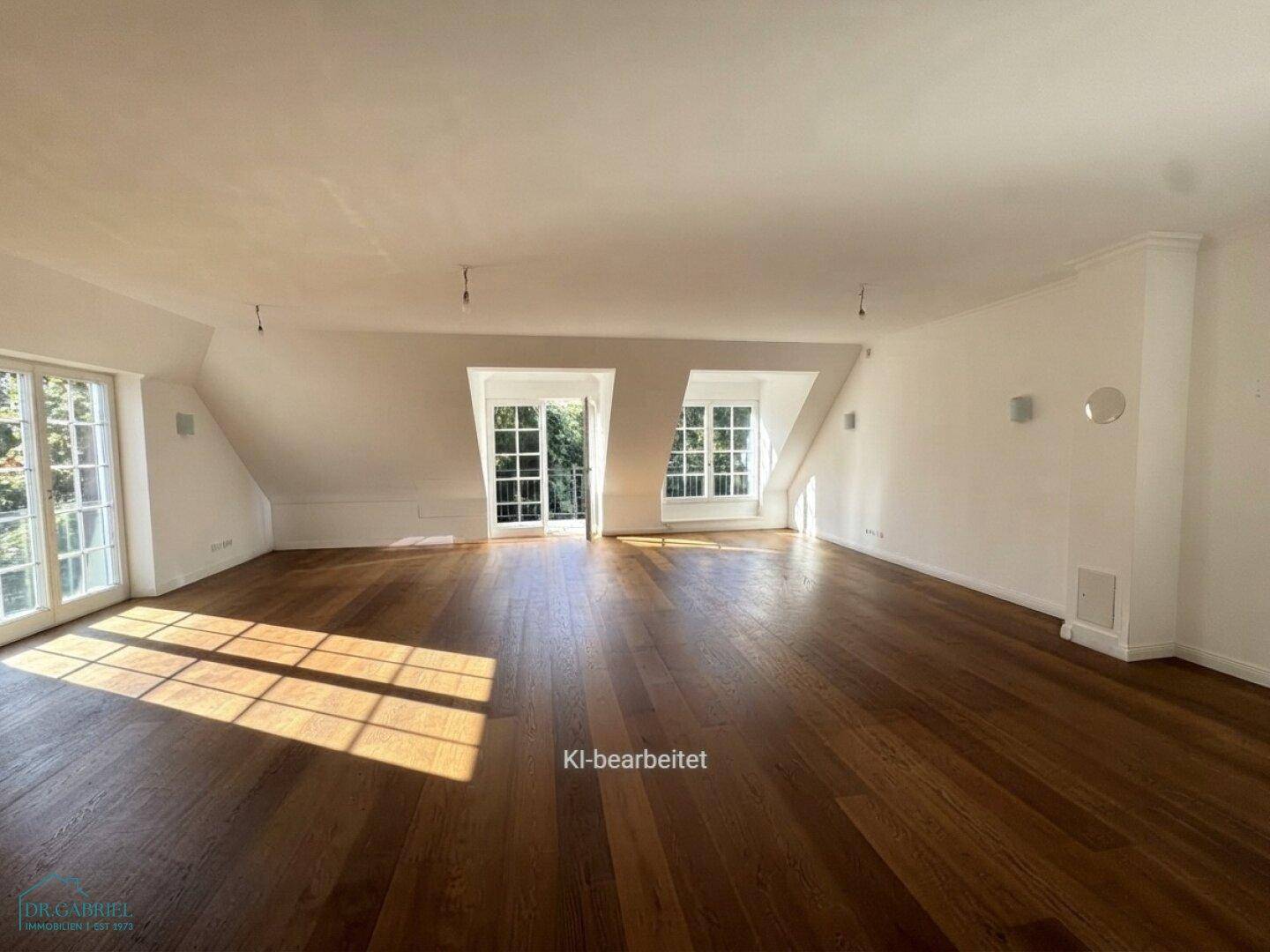 Geräumiger, leerer Wohnbereich im Dachgeschoss mit Holzboden und viel natürlichem Licht.
