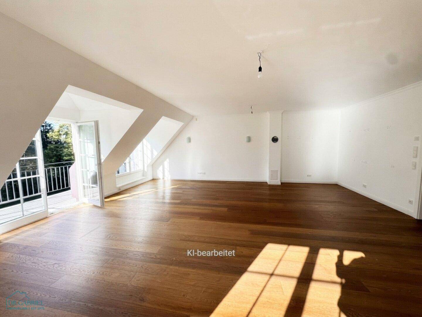 Lichtdurchfluteter Wohnbereich im Dachgeschoss mit Holzboden und direktem Balkonzugang.