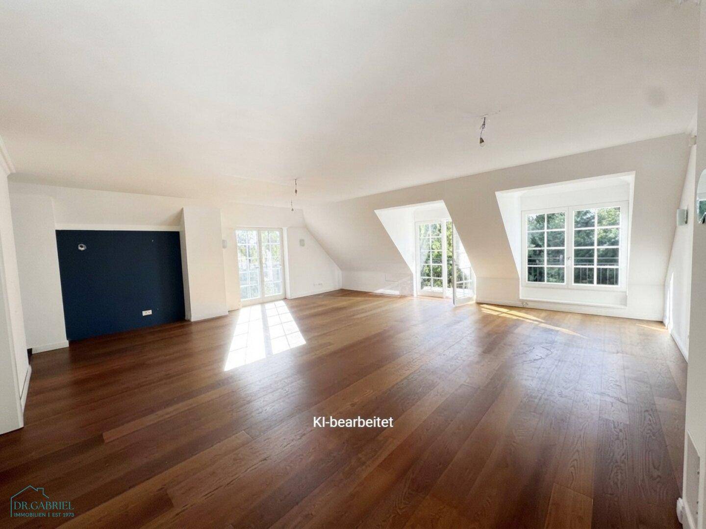 Großer, leerer Wohnbereich im Dachgeschoss mit Holzboden und einer blauen Akzentwand.