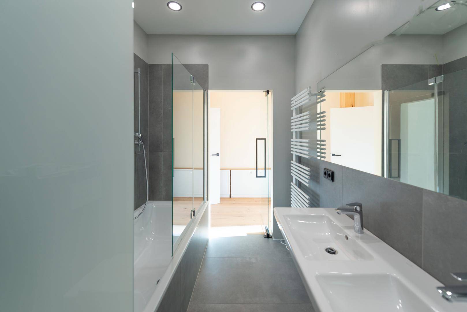 Helles modernes Badezimmer mit Badewanne, Einzelwaschbecken und beheiztem Handtuchhalter.