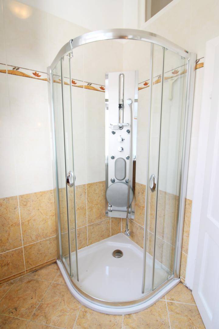 Modernes Badezimmer mit Eckduschkabine und hellbraunen Wand- und Bodenfliesen.
