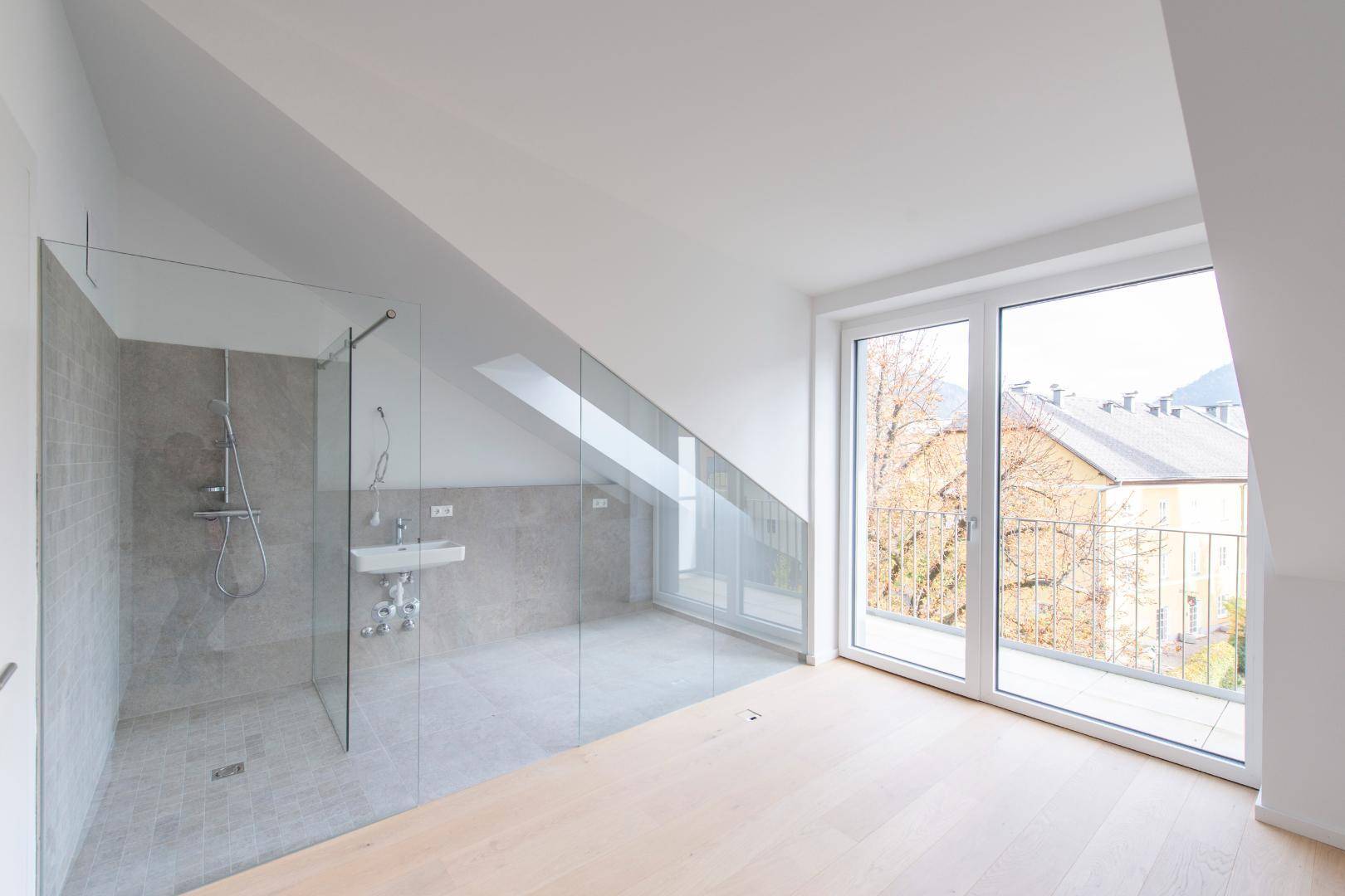 Geräumiges Badezimmer mit begehbarer Dusche, Waschbecken und Zugang zu einem Balkon.