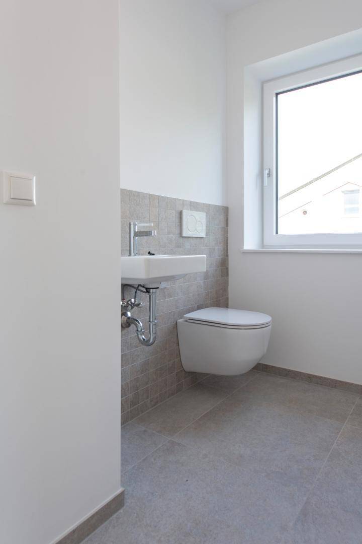 Modernes Gäste-WC mit wandhängender Toilette, Einzelwaschbecken und Fenster.