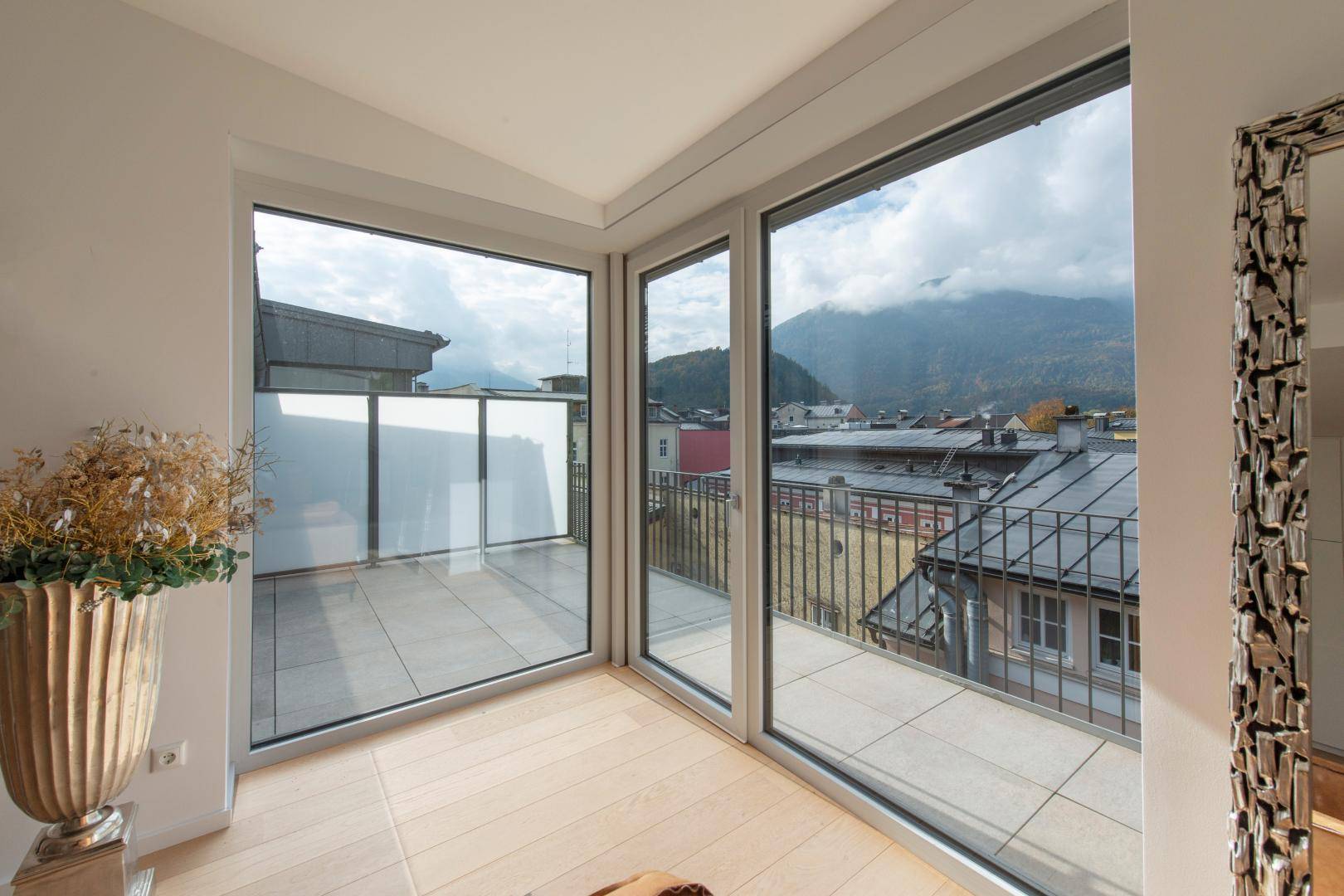 Große Fensterfront mit Zugang zu einem Balkon und weitem Blick auf die umliegende Berglandschaft.