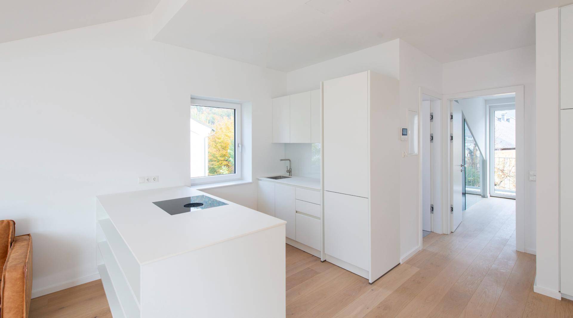Moderne, helle Küche mit weißen Schränken, Kochinsel und Fenster für natürliches Licht.