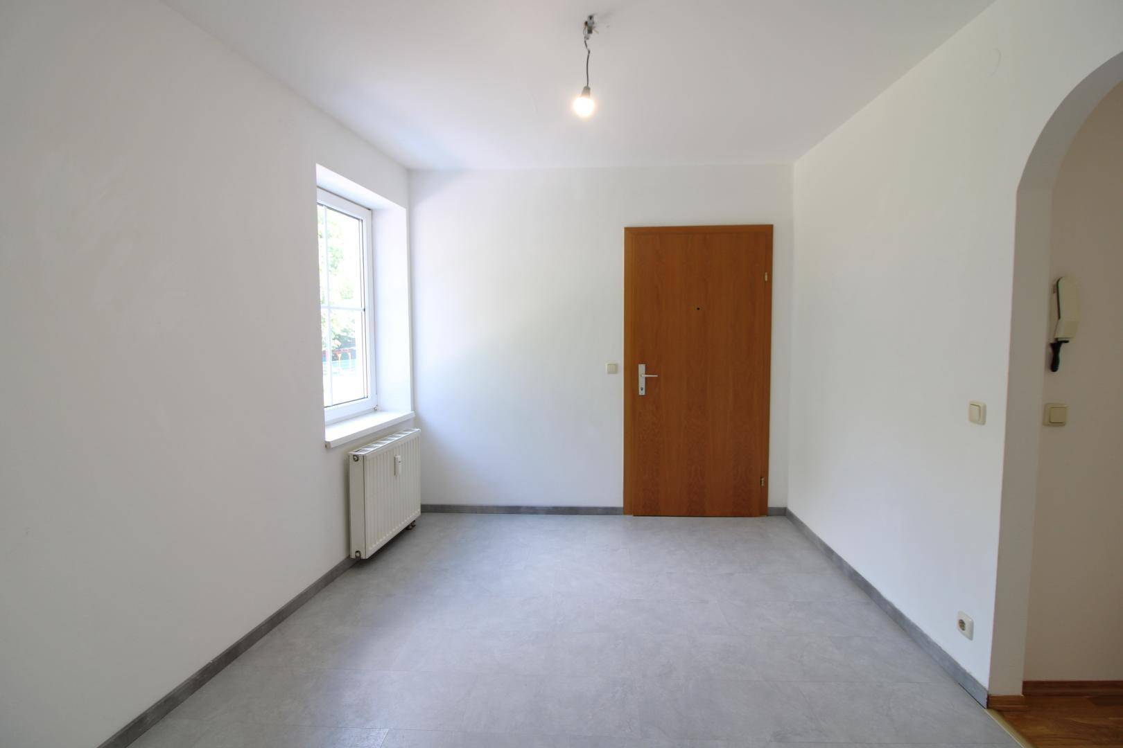 Heller Eingangsbereich oder Flur mit modernen Fliesen und einer Holztür.