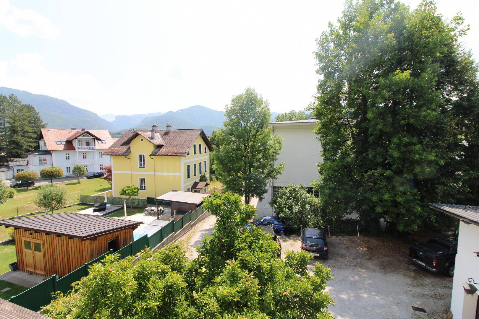 Weitblick über die Nachbarschaft mit Häusern, Bäumen und Bergen im Hintergrund.