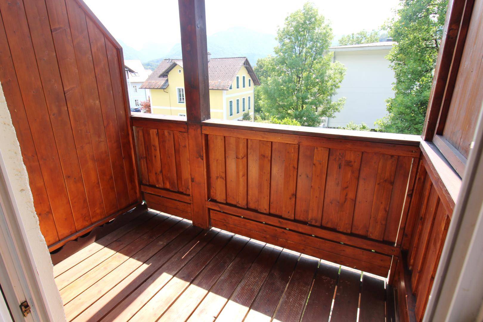 Gemütlicher Holzbalkon mit Blick auf die umliegenden Häuser und grüne Bäume.