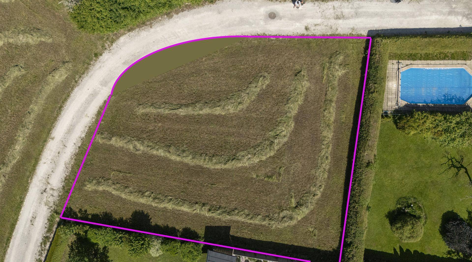 Detaillierte Luftaufnahme des Baugrundstücks mit angrenzendem Pool, Hecke und Zufahrtsweg.