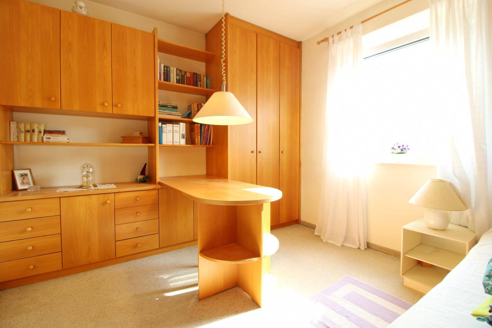 Helles Arbeitszimmer mit maßgefertigten Holzmöbeln, Regalen und viel Tageslicht.