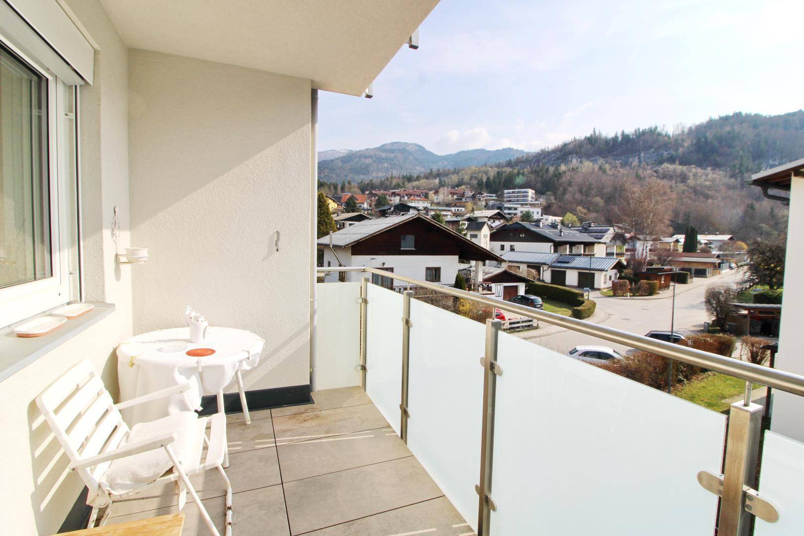 Sonniger Balkon mit Sitzgelegenheiten und weitem Blick über die Stadt und Berge.