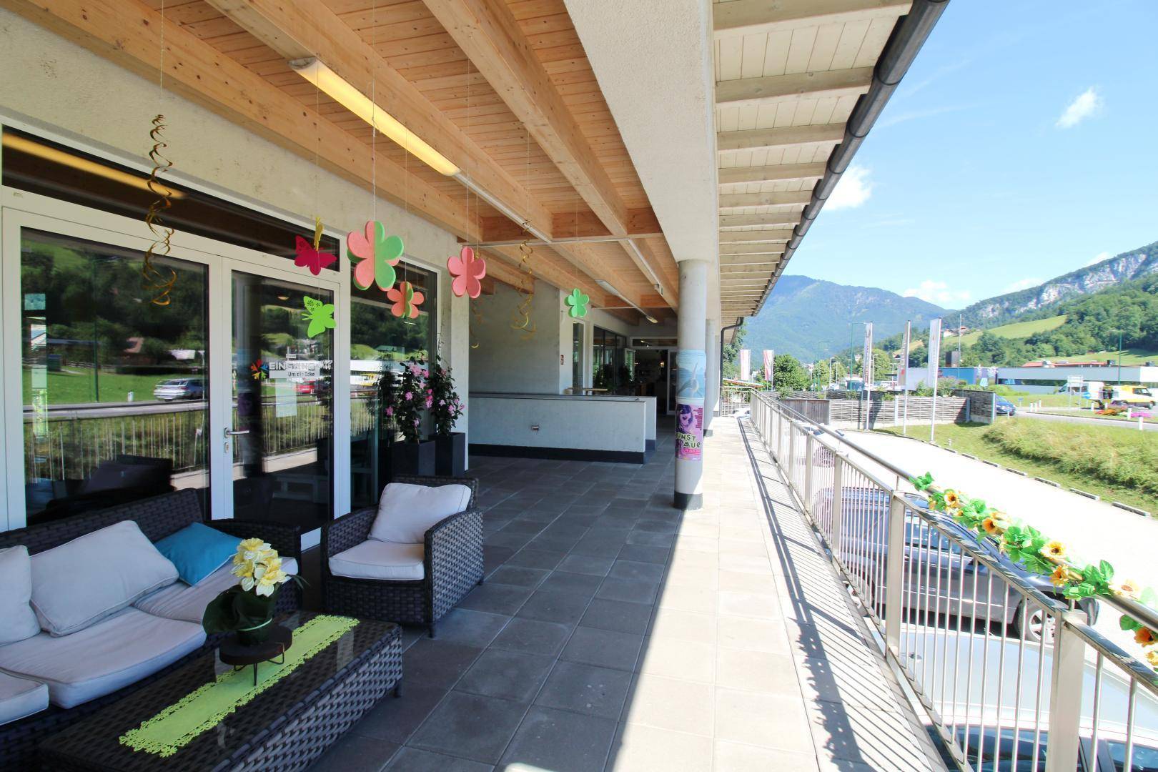 Überdachte Terrasse mit Rattanmöbeln und Blick auf die umliegende Berglandschaft.