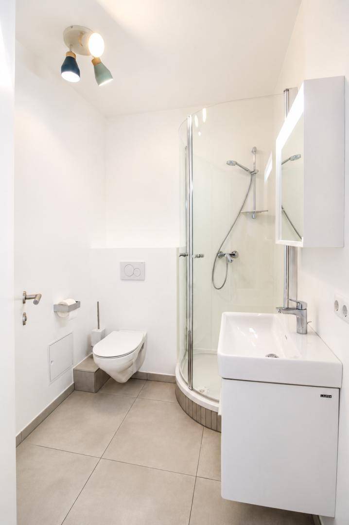 Modernes Badezimmer mit Duschkabine, wandhängendem WC und Waschbecken mit Unterschrank.