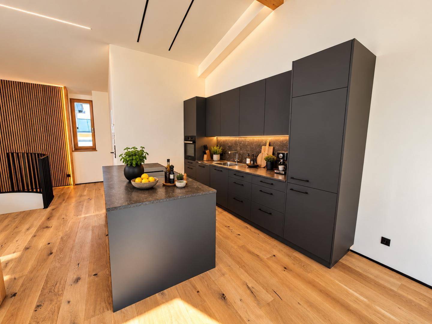 Moderne Küche mit dunklen Schränken, Kücheninsel und Holzboden in offenem Wohnbereich.