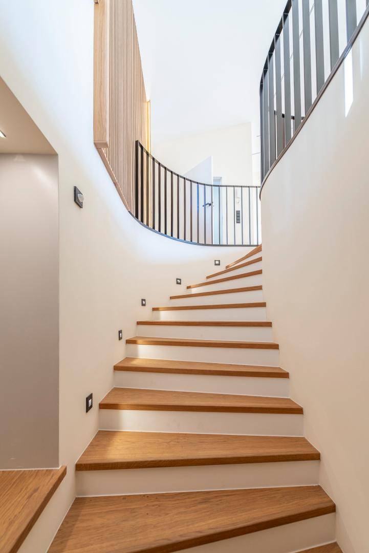 Moderne Holztreppe mit elegantem Geländer und integrierter Beleuchtung im Flurbereich.