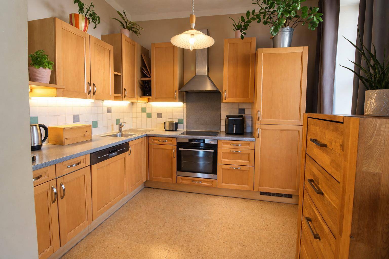 Funktionale Küche mit Holzschränken, modernen Geräten und ausreichend Arbeitsfläche.