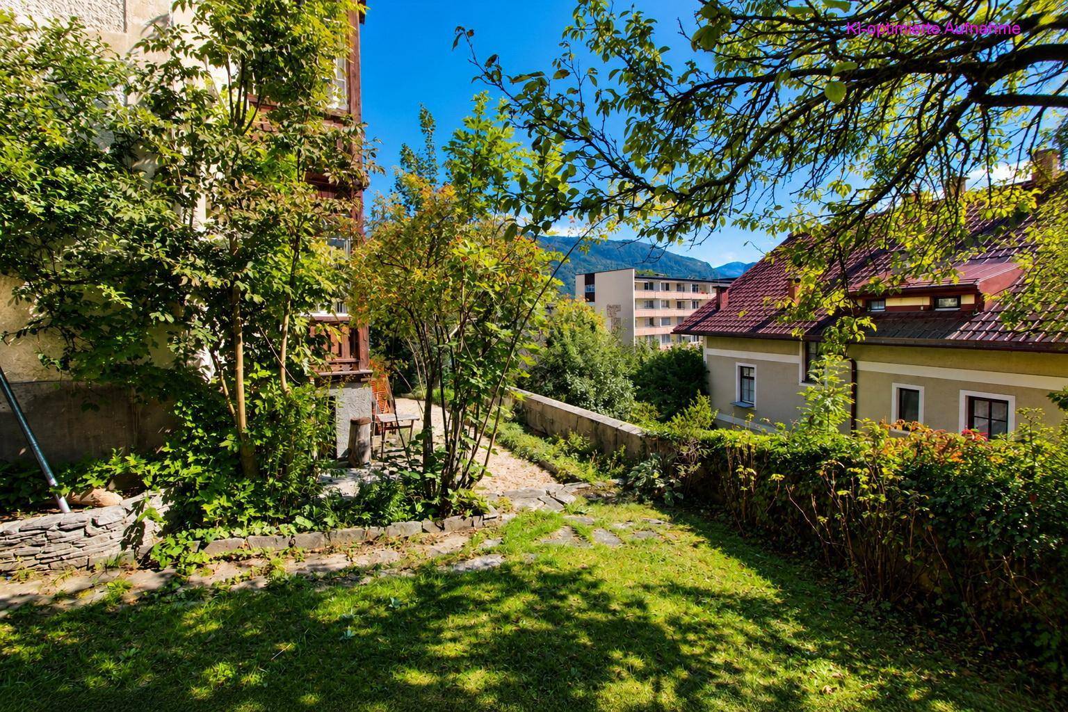 Seitlicher Gartenweg entlang des Hauses mit üppiger Vegetation und Blick auf die Nachbarschaft.