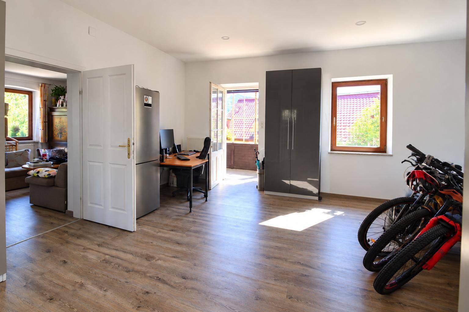 Heller Eingangsbereich mit Laminatboden, Stauraum und Zugang zu einem Balkon.