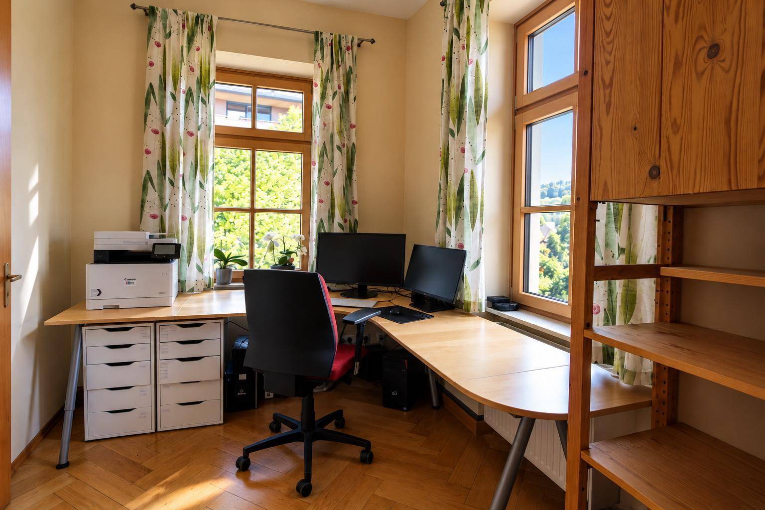 Helles Arbeitszimmer mit Holzparkett, großem Schreibtisch und Blick ins Grüne.