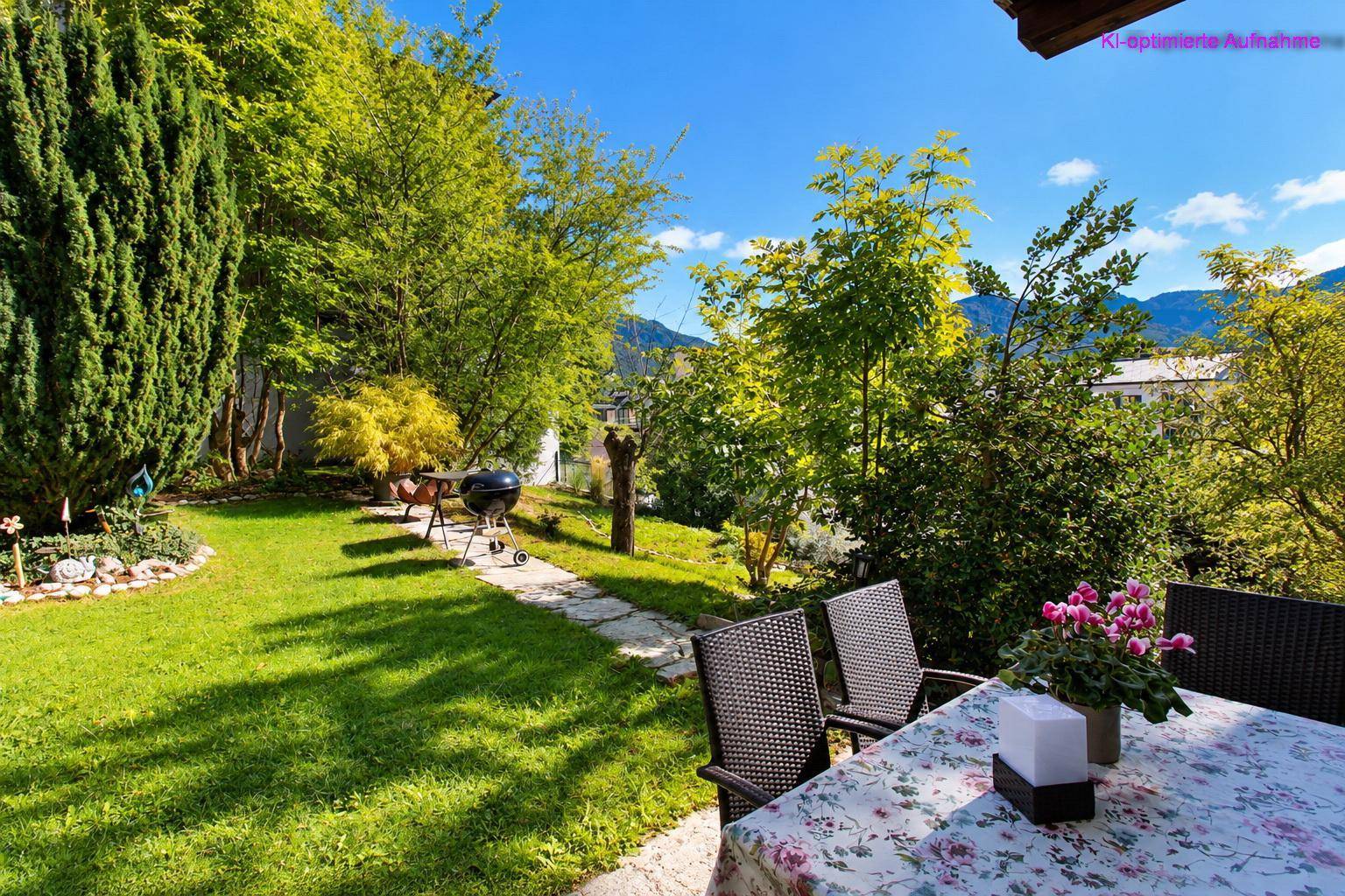 Gemütlicher Sitzbereich im Garten mit Grill und weitem Blick auf die grüne Landschaft.