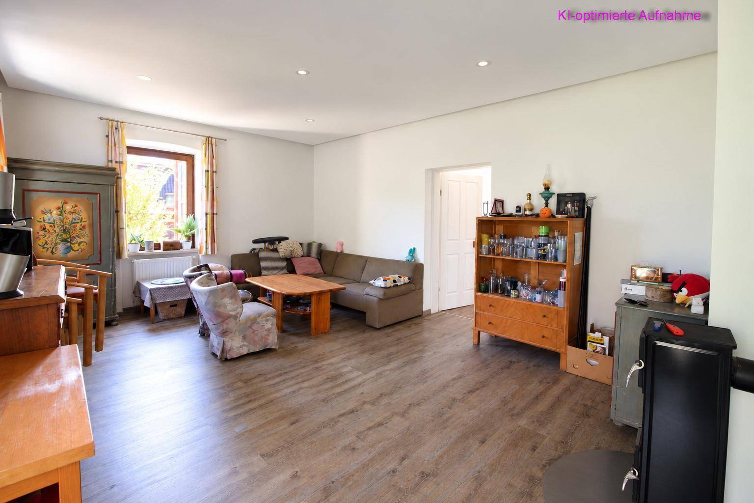Geräumiges Wohnzimmer mit Laminatboden, gemütlicher Sitzecke und hellem Ambiente.