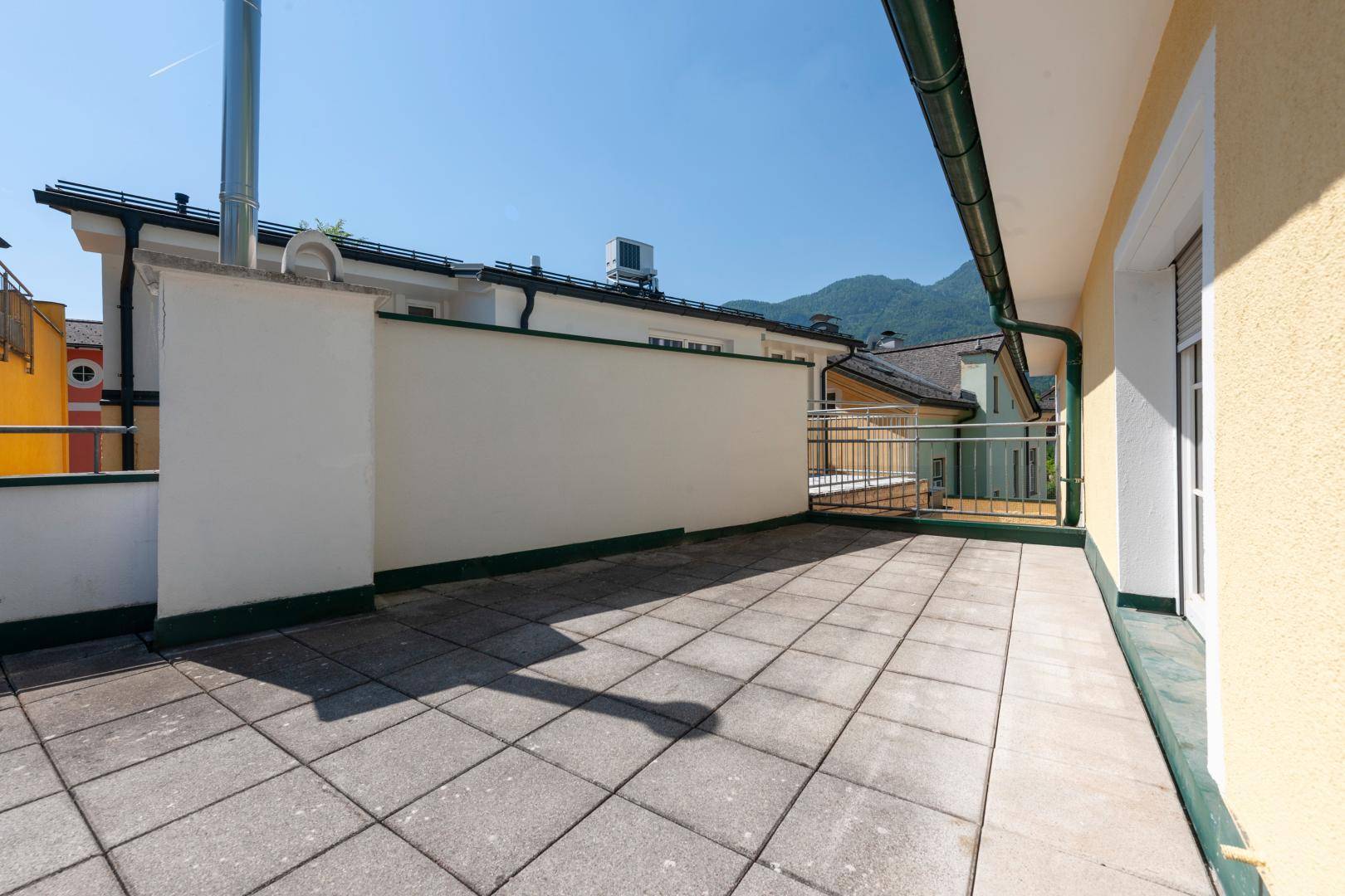 Geräumige Außenterrasse mit Fliesenboden und Blick auf die umliegende Berglandschaft.