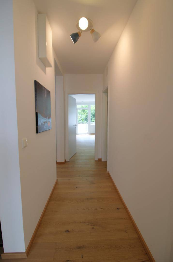 Langer, heller Flur mit Holzboden, der zu den verschiedenen Räumen der Wohnung führt.
