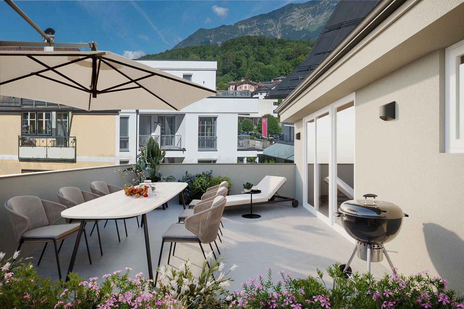 Geräumige Dachterrasse mit Essbereich, Grill und Liegestuhl, umgeben von Blumen und Bergblick.