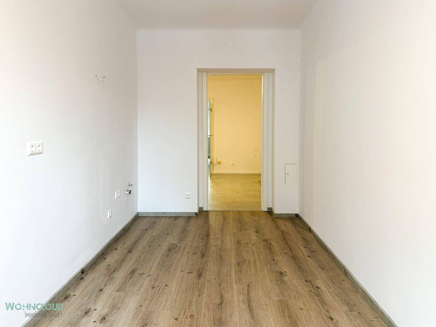 Leeres Zimmer mit Holzboden und offener Tür, bietet flexible Raumgestaltung.