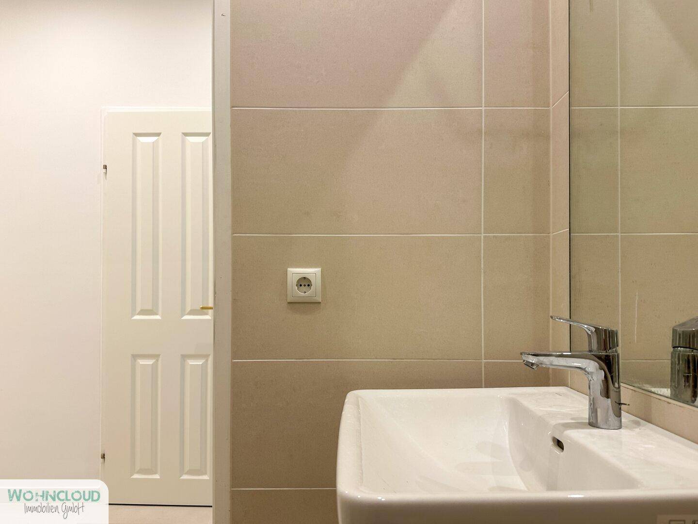 Detailansicht des modernen Waschbeckens mit Armatur und beigen Wandfliesen im Badezimmer.