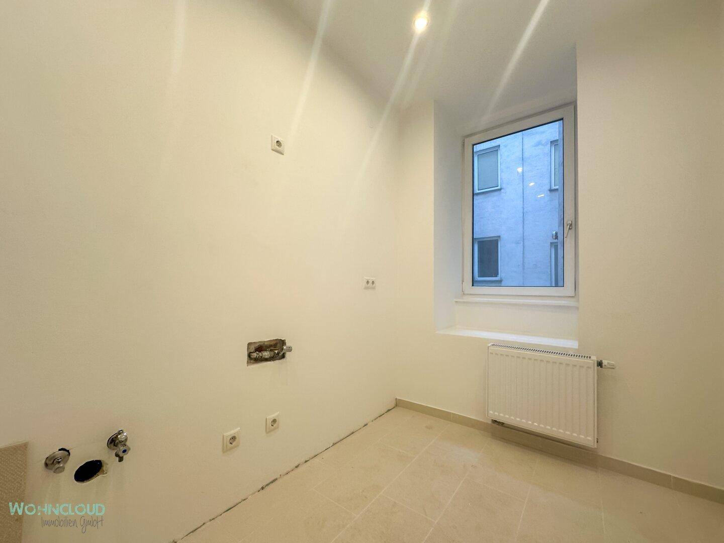 Leerer Raum mit Anschlüssen für eine Küche und Fenster.
