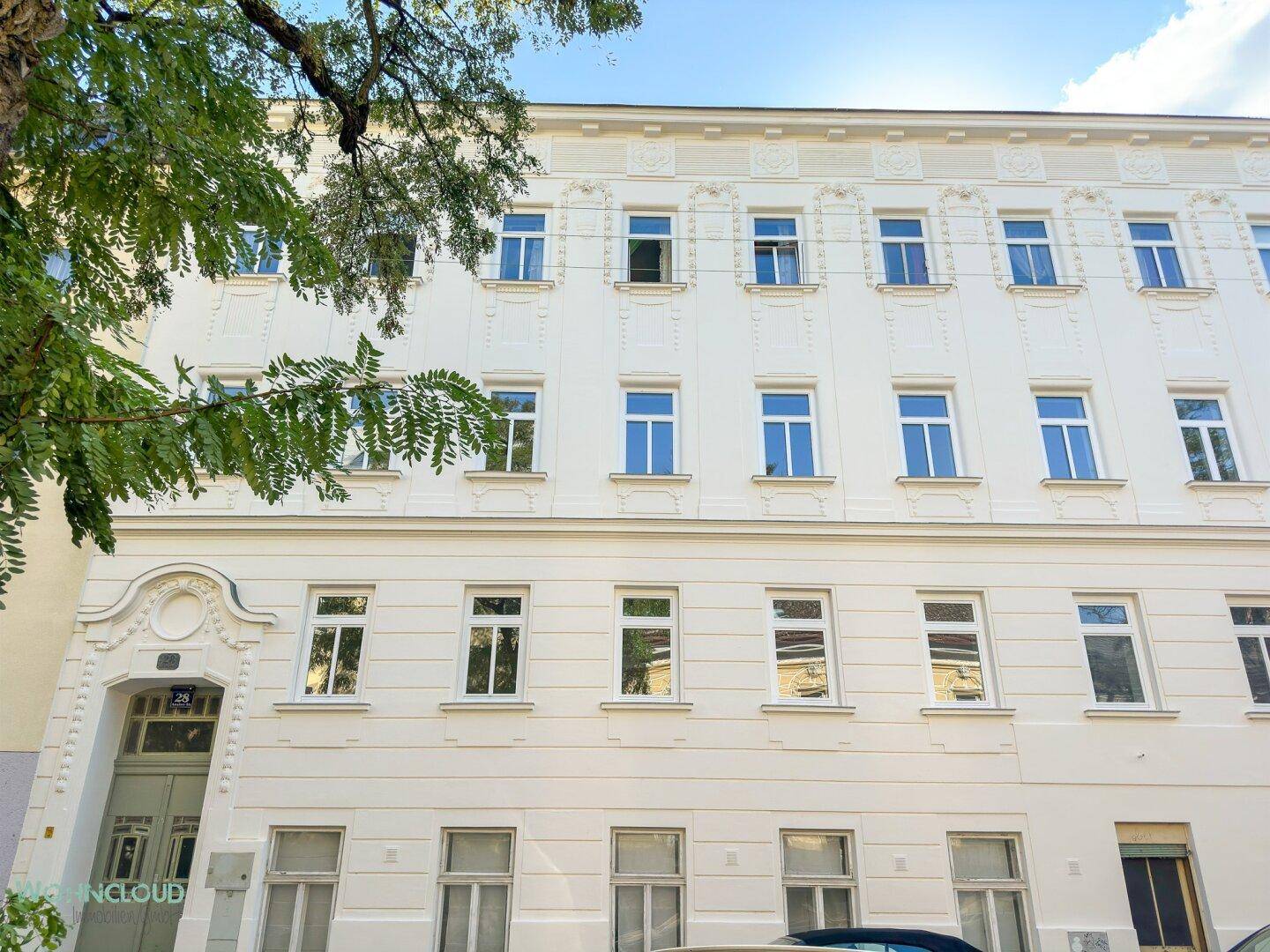 Klassische Fassade eines Mehrfamilienhauses mit vielen Fenstern und architektonischen Details.