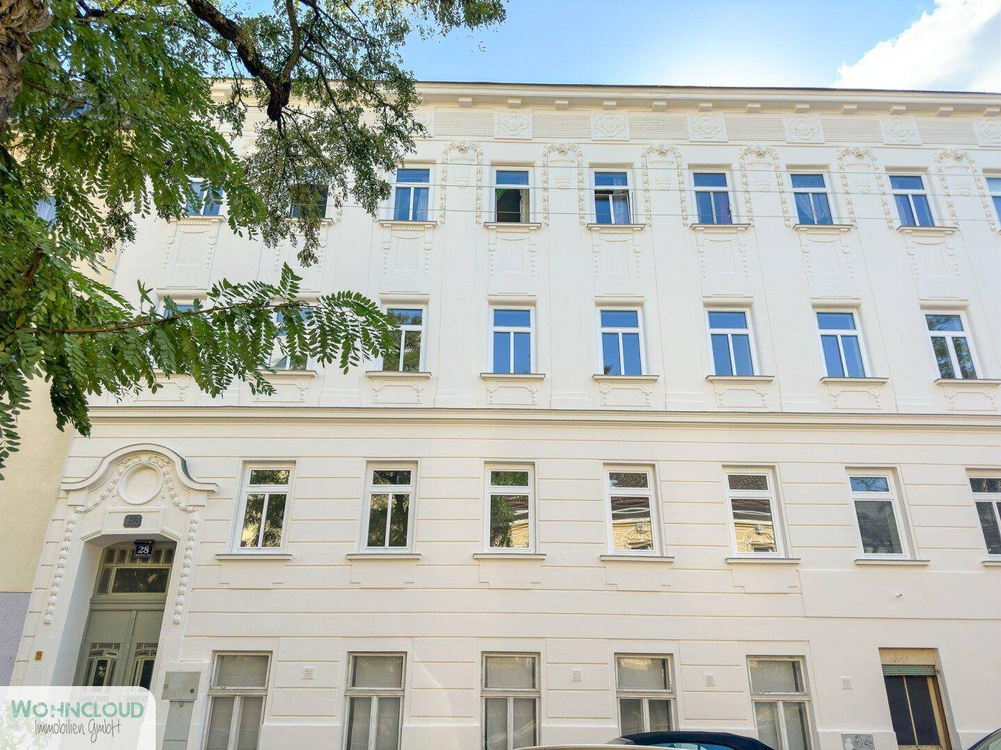 Klassische Fassade eines Altbaus mit zahlreichen Fenstern und dekorativen Elementen.