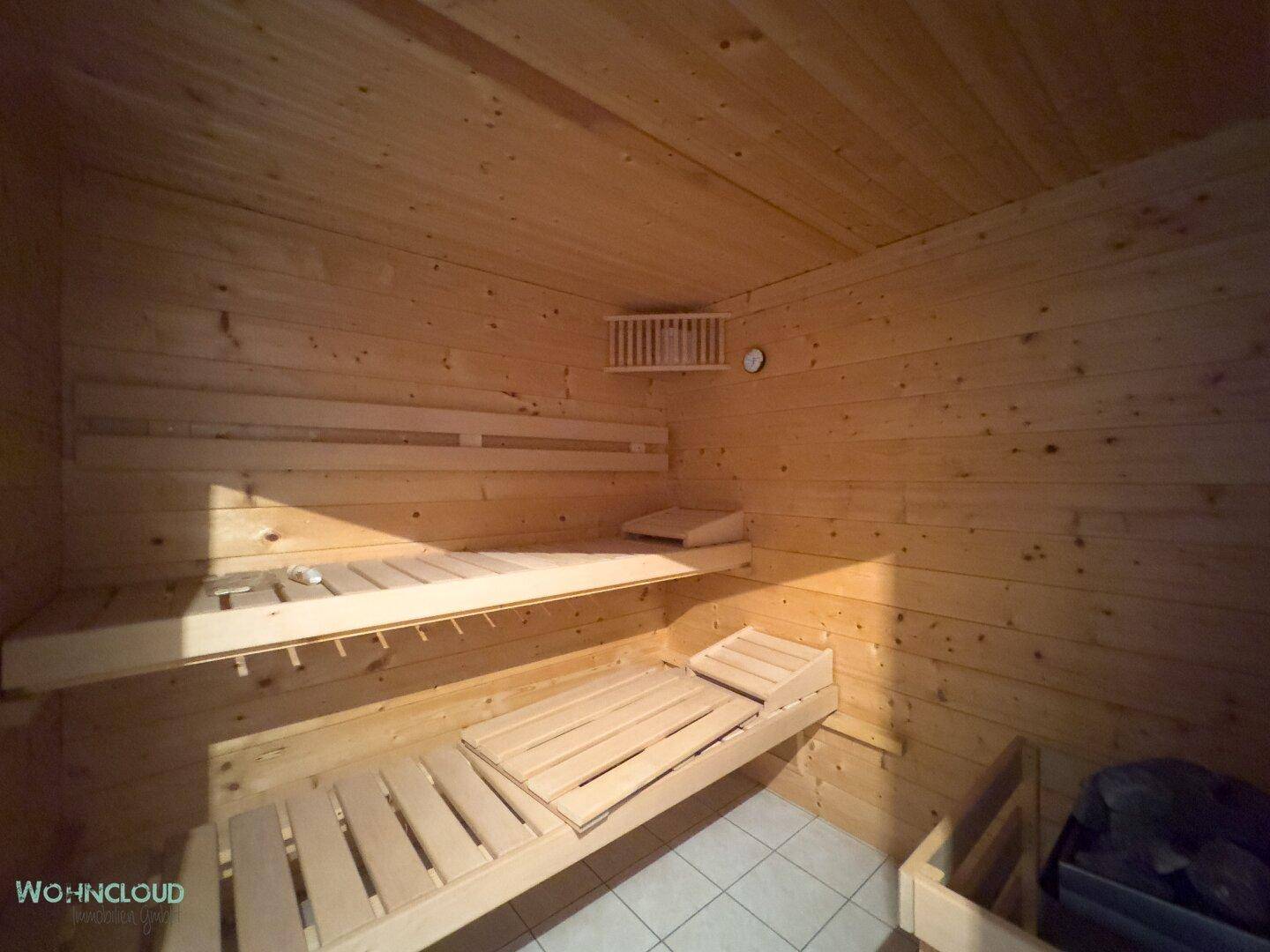 Holzvertäfelte Sauna mit Bänken und Heizofen für entspannende Wellnessmomente.