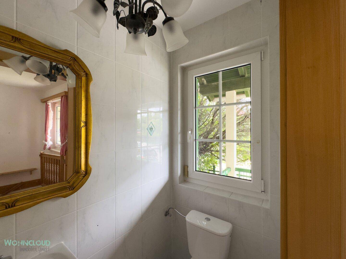 Kleines Gäste-WC mit Fenster, weißen Fliesen und einem dekorativen Spiegel.
