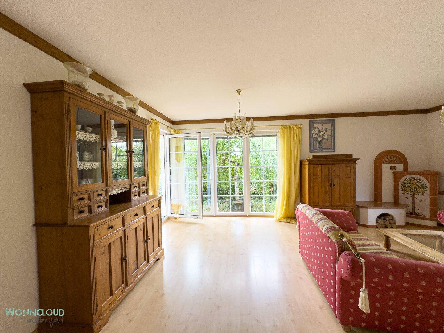 Geräumiges Wohnzimmer mit traditionellen Holzmöbeln, Kamin und Zugang zum Garten.