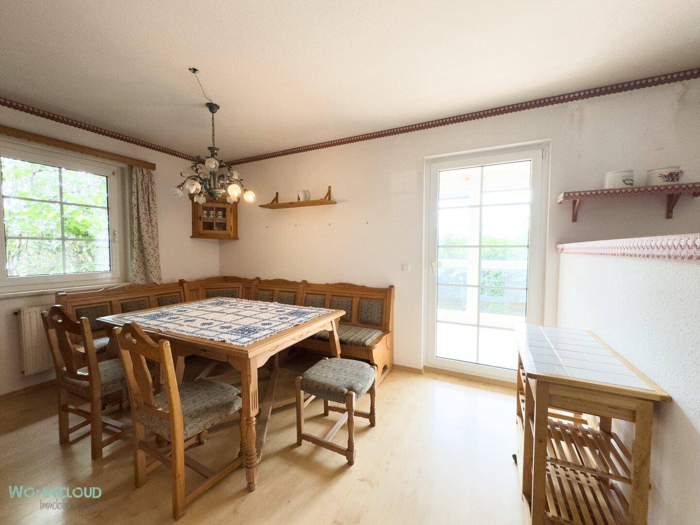 Essbereich mit rustikaler Eckbank, Holztisch und Zugang zu einem Außenbereich.