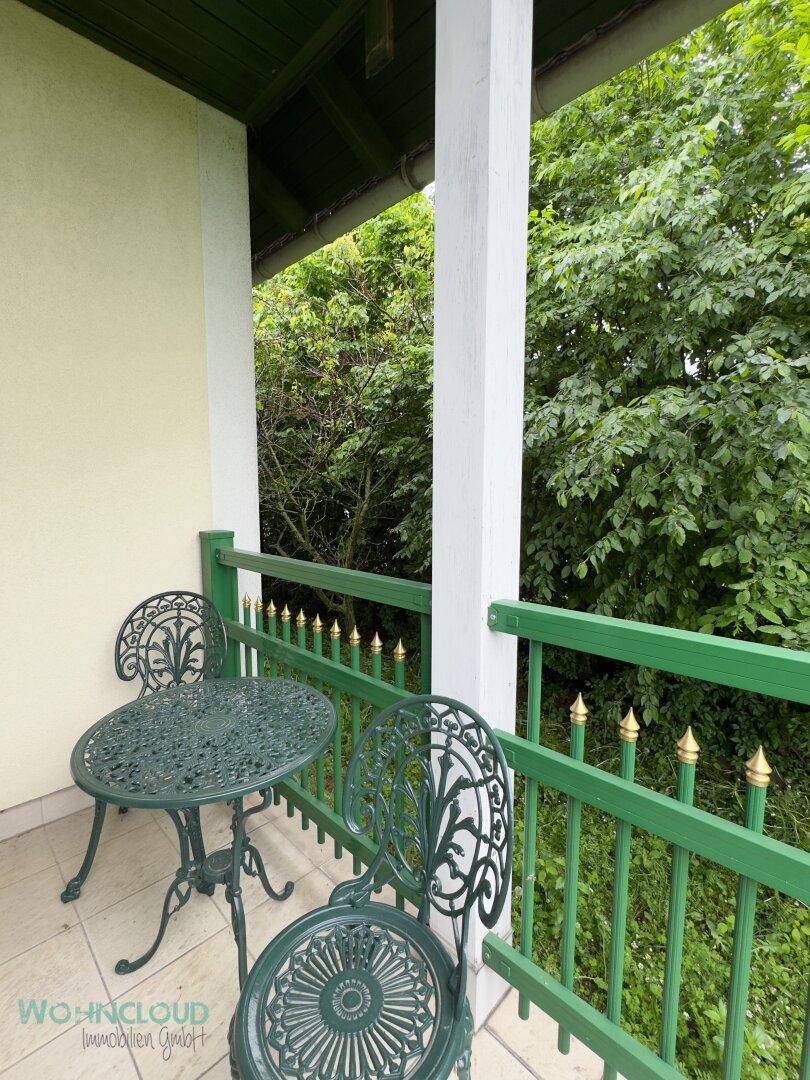Kleiner Balkon mit schmiedeeisernen Möbeln und Blick ins Grüne.