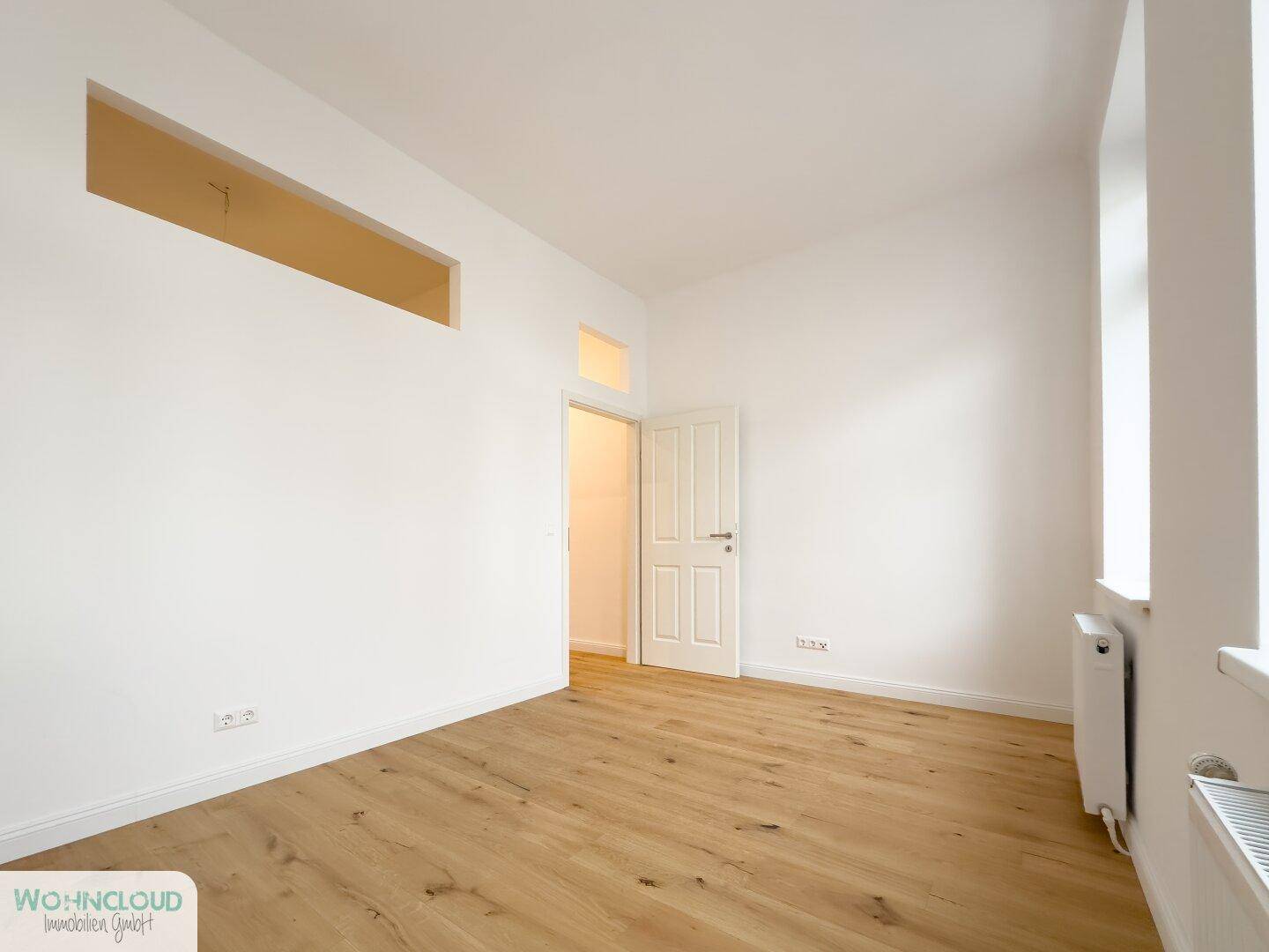 Helles, leeres Zimmer mit Parkettboden und Heizkörper, bereit zur individuellen Gestaltung.