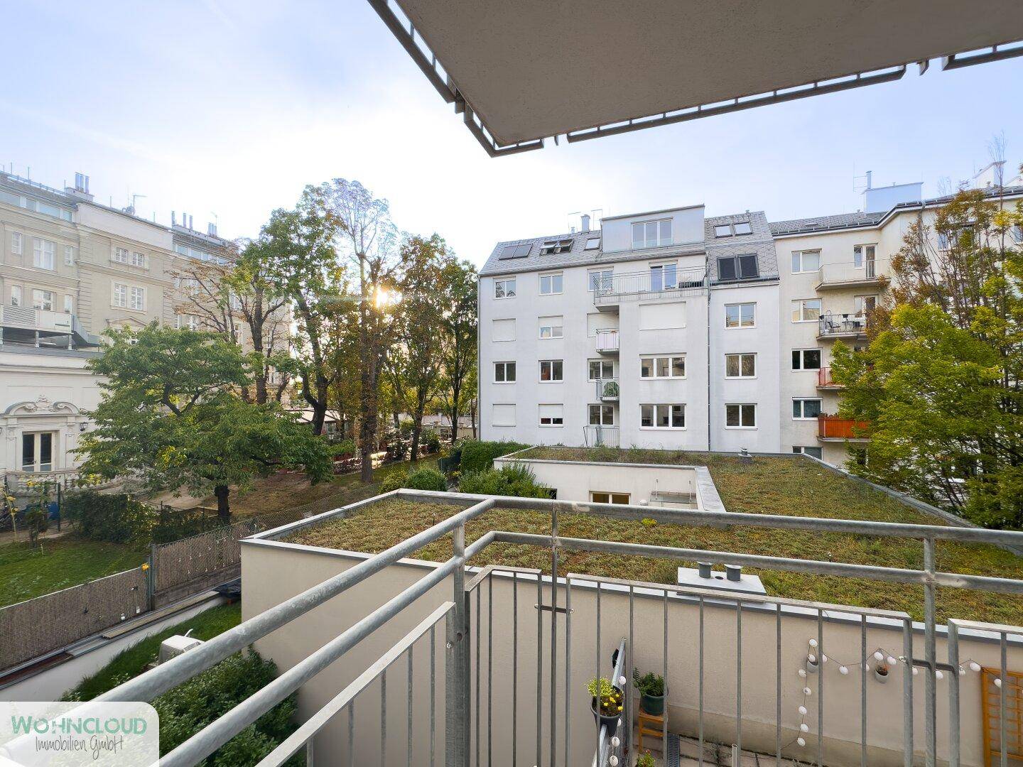 Balkon mit Blick auf die umliegenden Gebäude und eine begrünte Dachfläche.